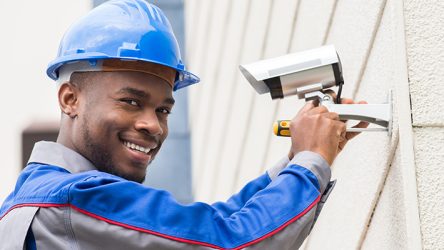 Young Happy Male Technician Repairing Camera With Screwdriver